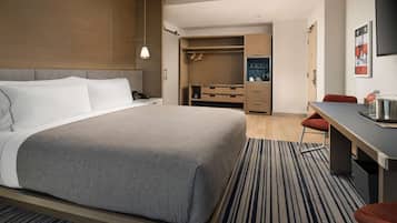 A modern hotel room with a large bed, a desk, and a walk-in closet.