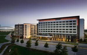A modern hotel with a flat roof, multiple floors, and a well-lit entrance. - Canopy by Hilton Dallas Frisco Station, TX (Frisco)