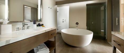 A modern bathroom with a large freestanding bathtub, a double vanity with a mirror, and a walk-in shower.