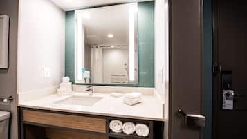 A hotel bathroom with a large mirror, a sink, and a towel rack.