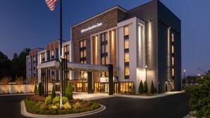 Un hotel moderno con entrada despejada, una bandera estadounidense y un cartel que dice "Hilton Garden Inn".