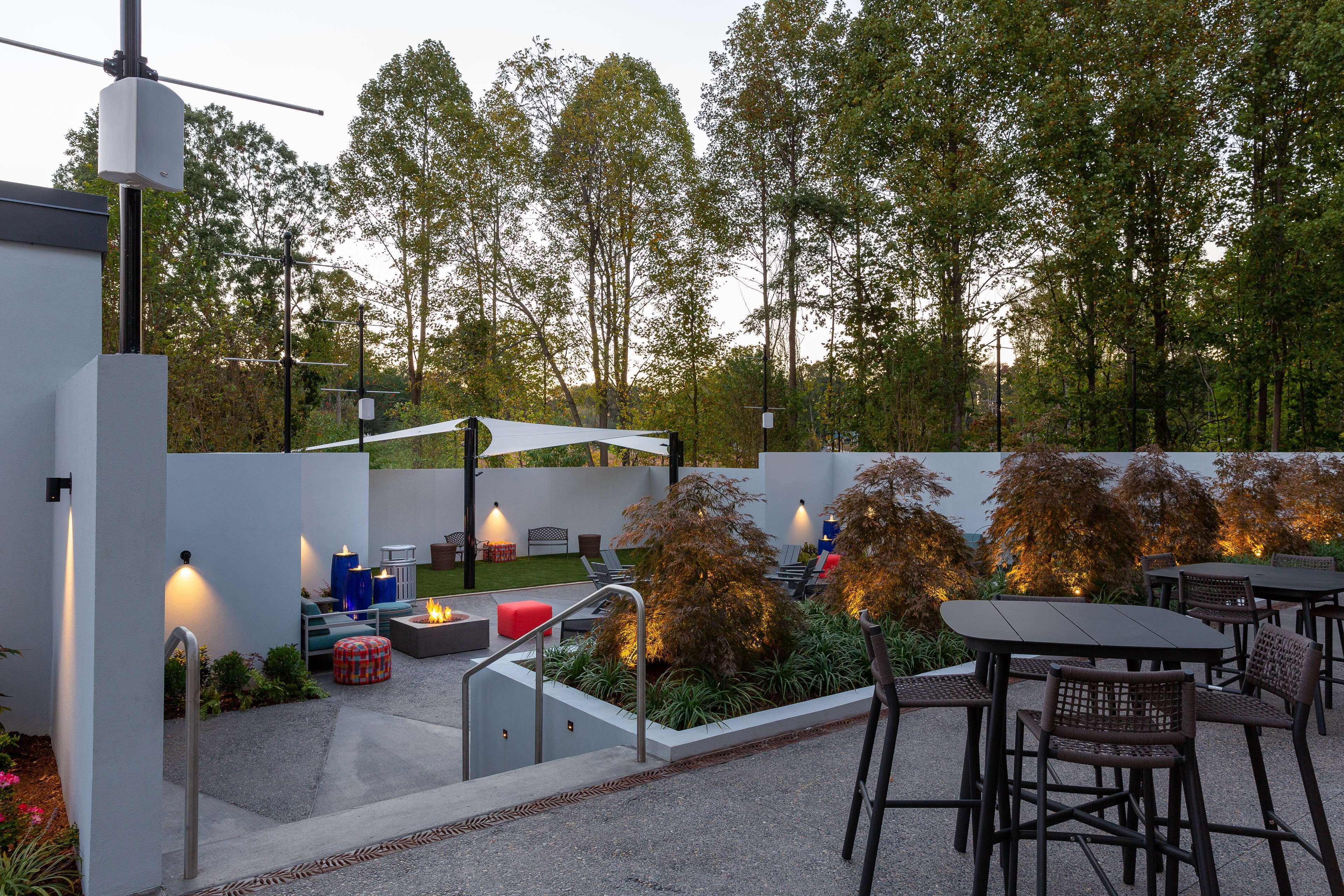 Un espacio al aire libre con patio amoblado, una chimenea y un toldo blanco.