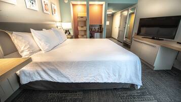 A hotel room with a large bed, a TV, a desk, and a wardrobe.