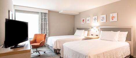 A hotel room with two beds, a TV, a desk, and a chair.