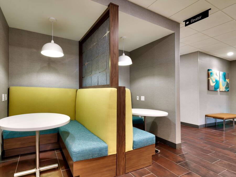 A modern hotel lobby with a seating area featuring a wooden bench and a round table.