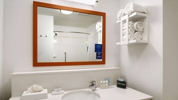 A bathroom with a large mirror, a sink, and a towel rack with neatly rolled towels.
