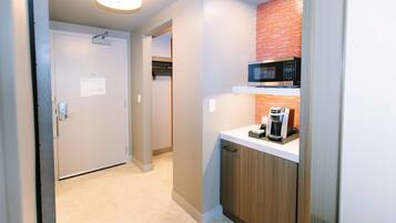 A narrow hallway leading to a kitchen area with a microwave and coffee maker on a countertop.