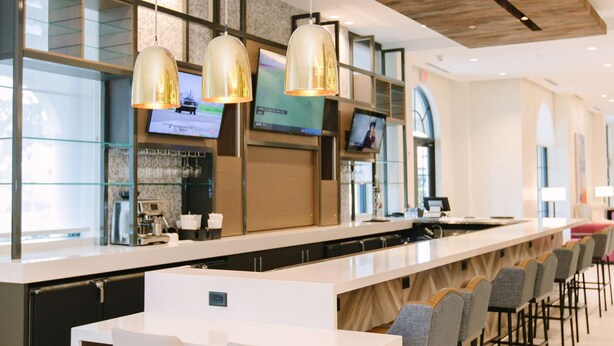 Un bar moderno con una barra larga, diversas opciones de asientos e iluminación colgante.