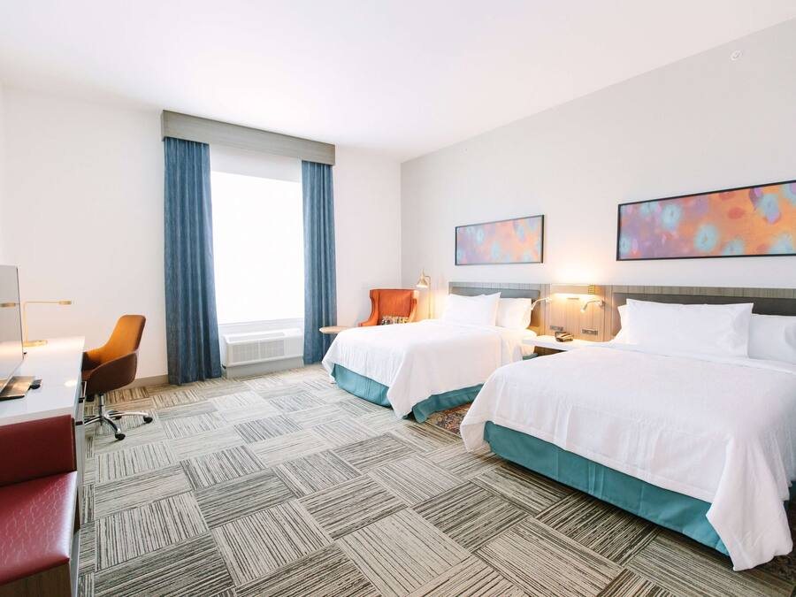Een hotelkamer met twee bedden, een bureau, een stoel en een televisie.