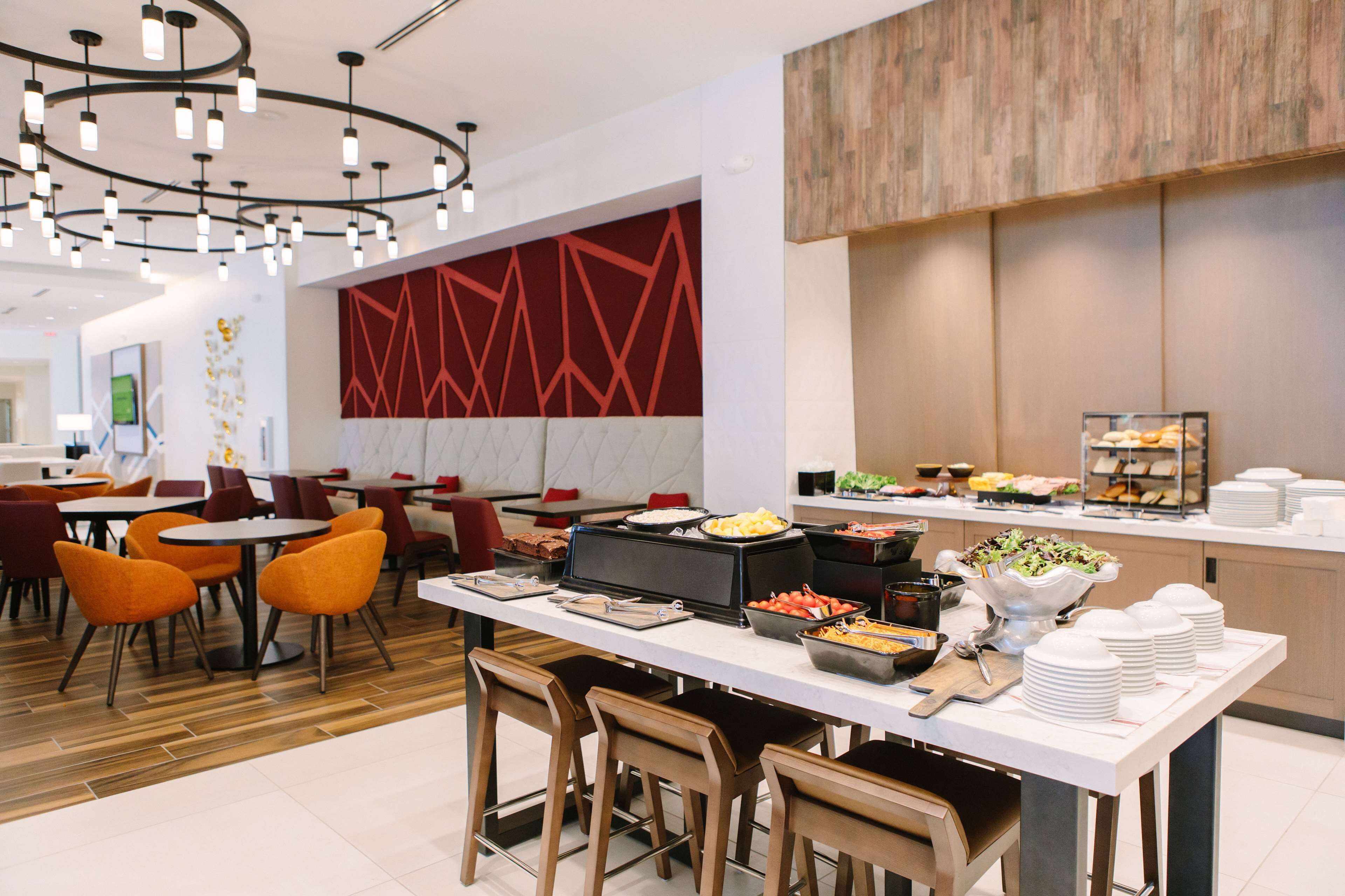 Un moderno comedor con barra libre, que incluye distintas estaciones de comida y diferentes disposiciones de asientos.