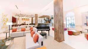 Un amplio salón con un piano de cola, un moderno conjunto de sofás y un gran pilar de madera.