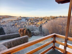 Vista desde un balcón sobre un pueblo cubierto de nieve, con casas y árboles.