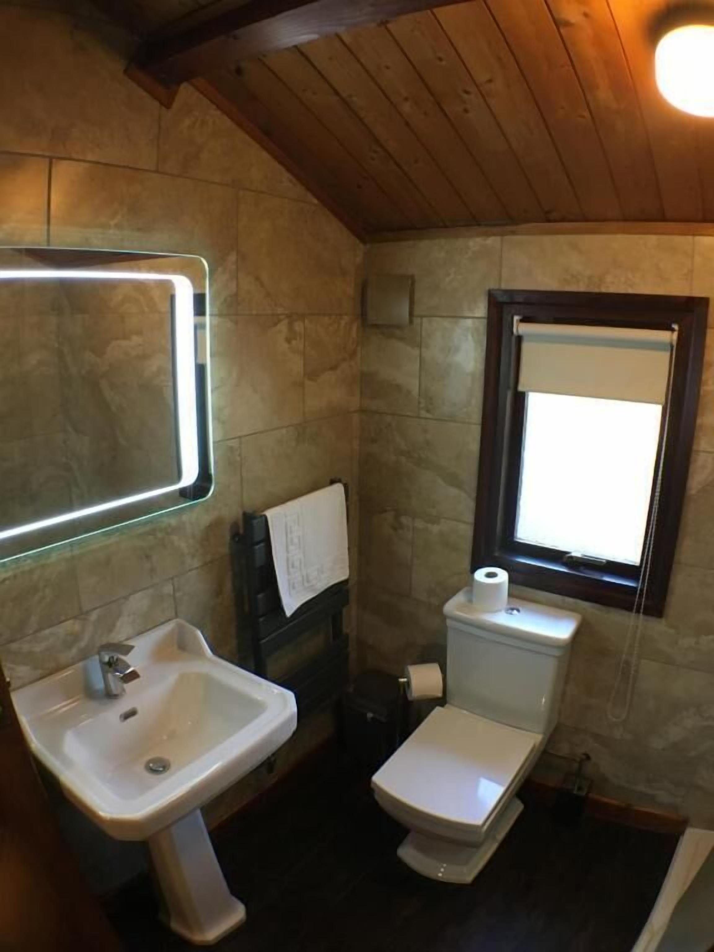 Une salle de bain avec un lavabo, des toilettes et une fenêtre.