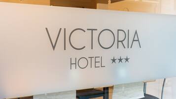 A reception desk with the sign "VICTORIA HOTEL" and three stars indicating a three-star rating.