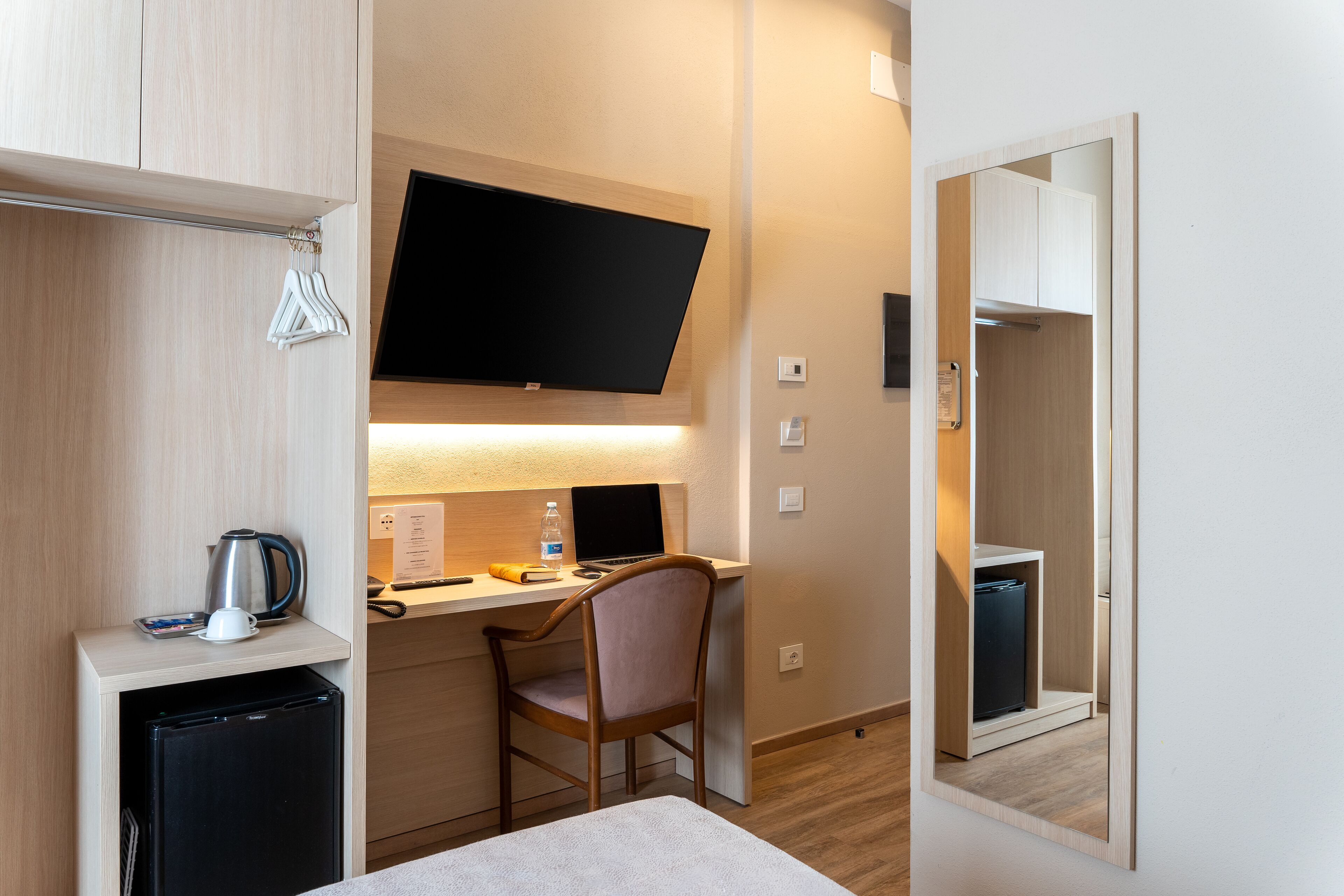 A compact room with a desk, chair, and a small refrigerator.