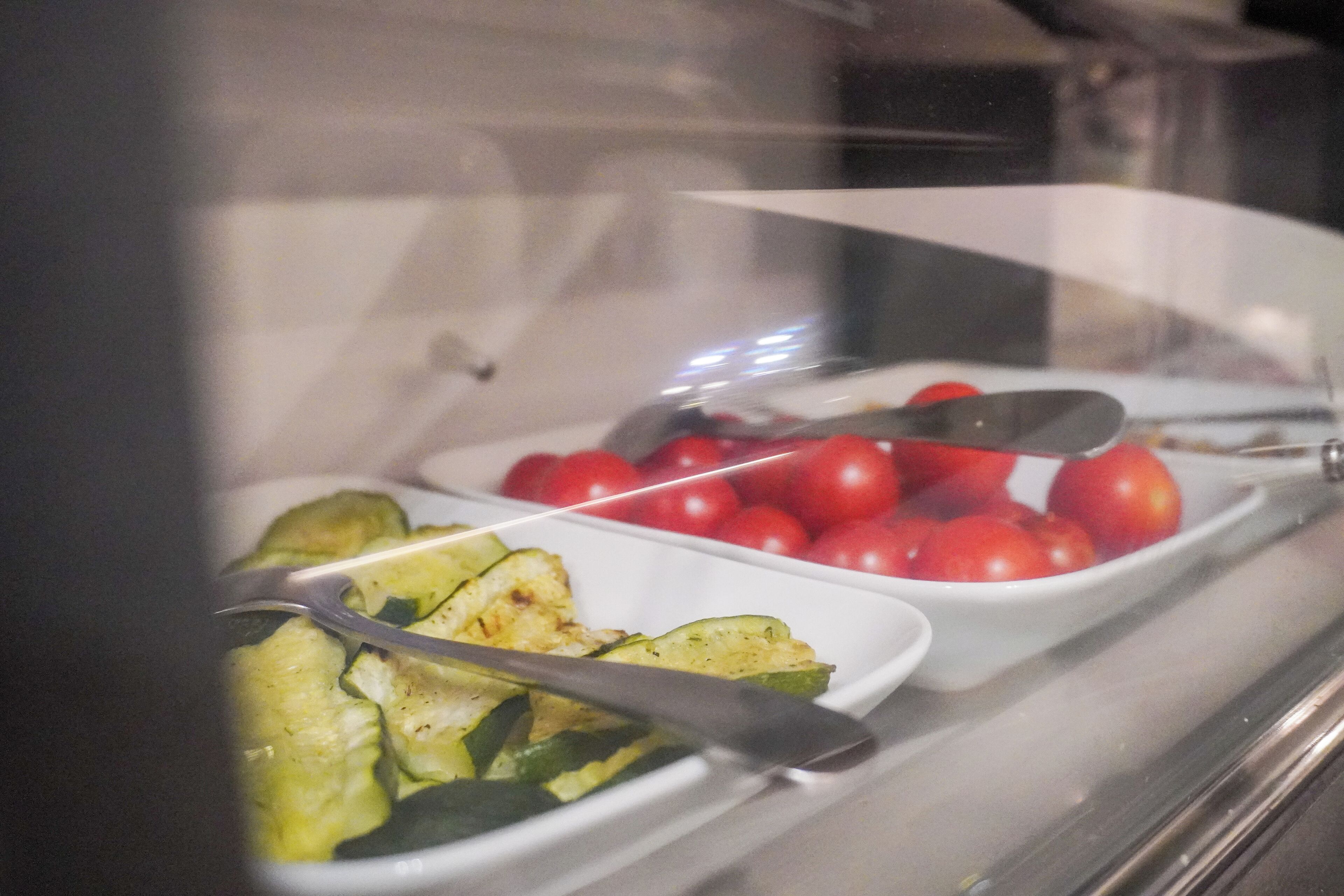 Un bufé con diversos platos, incluyendo verduras y tomates.