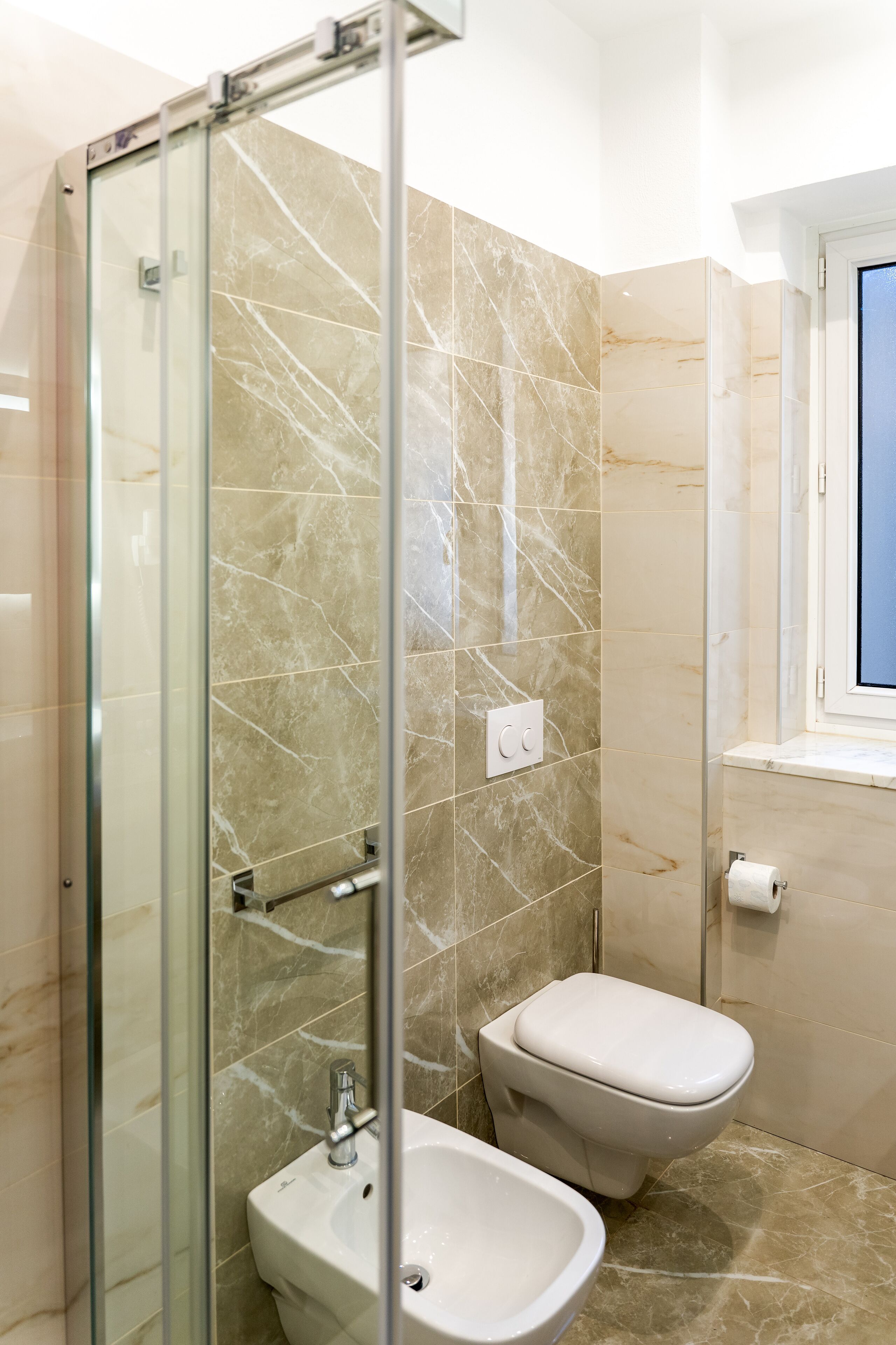 Un baño con cabina de ducha de vidrio, inodoro y lavabo.