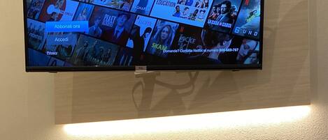 A modern hotel room with a flat-screen TV mounted on the wall displaying a Netflix interface.