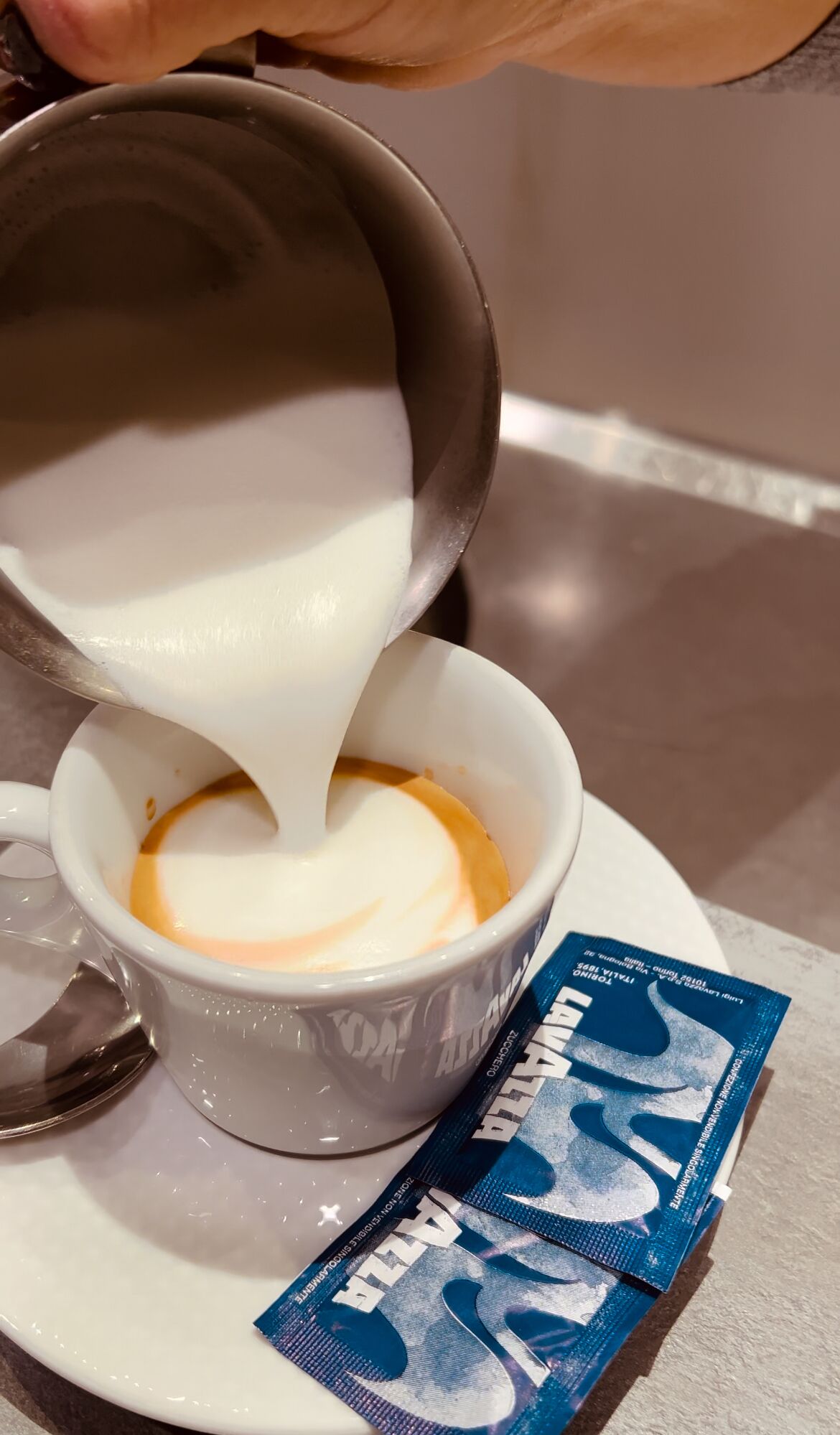 A cup of coffee with milk being poured into it.