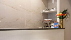 Una cocina moderna con encimeras de mármol, una cafetera y dos taburetes de bar.
