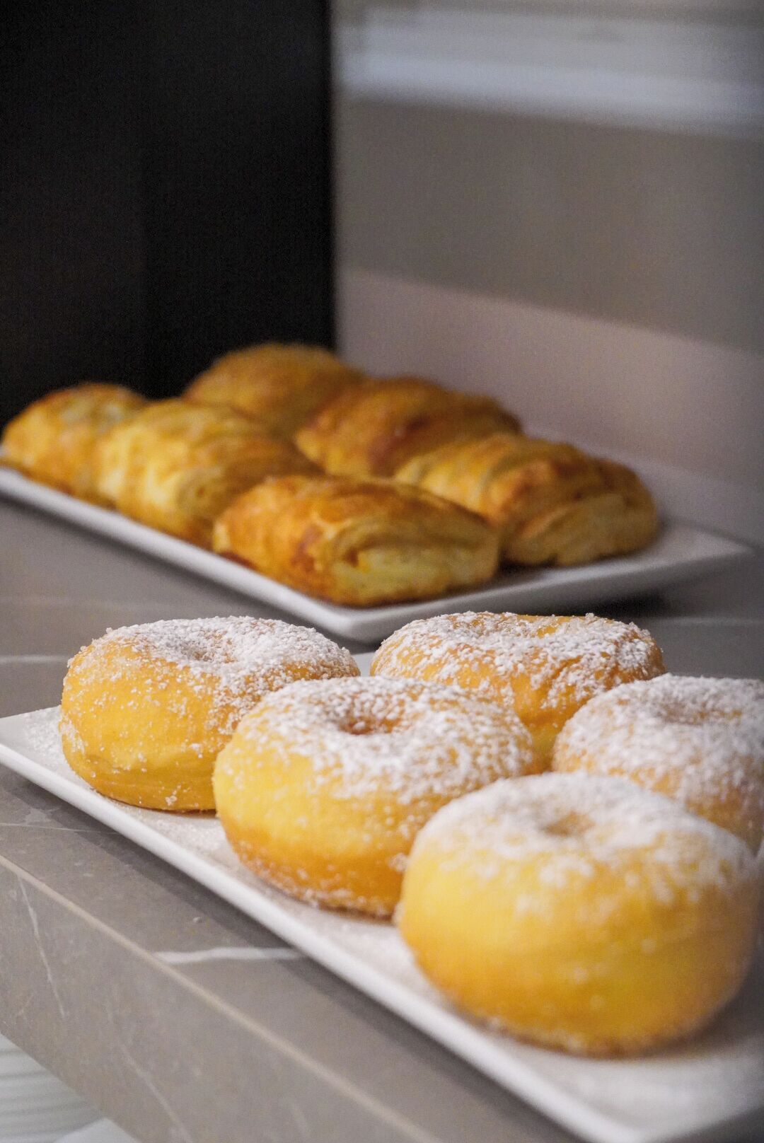 Una bandeja de pasteles, incluyendo rosquillas y cruasanes, sobre un plato blanco.