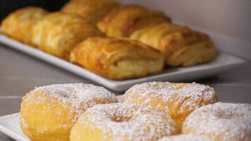 Una bandeja de pasteles, incluyendo rosquillas y cruasanes, sobre un plato blanco.