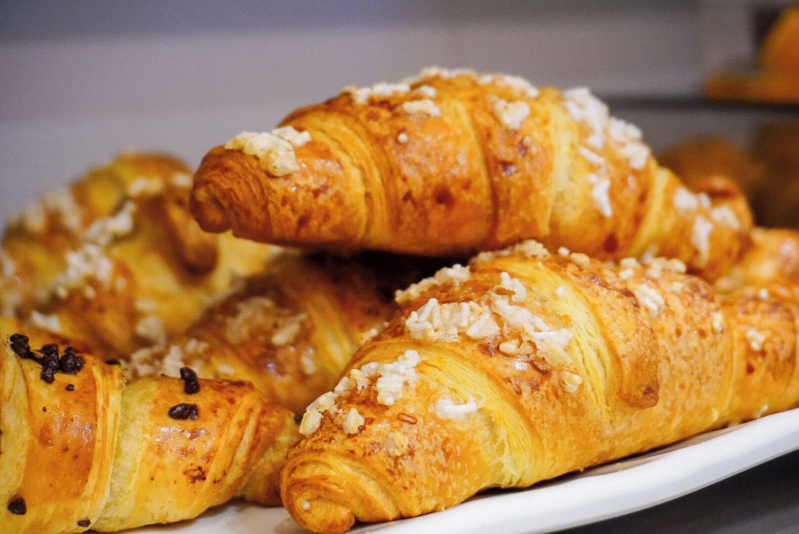 A plate of croissants with chocolate chips and nuts.