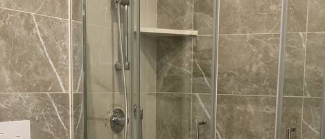 Une salle de bain moderne avec une douche à parois de verre, des toilettes et un porte-serviettes.