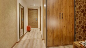 A hallway with wooden doors, a red bench, and a stone wall. - Newway Hotel (Kocasinan)