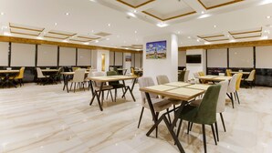A spacious dining area with marble flooring and modern furniture, featuring multiple tables and chairs arranged for groups. - Newway Hotel (Kocasinan)