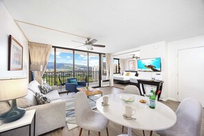 Ein modernes Hotelzimmer mit Balkon, Essbereich und Fernseher.