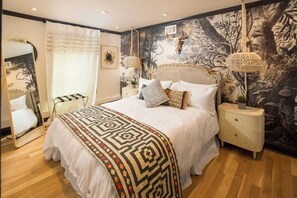 A bedroom with a large bed, a nightstand, a dresser, a mirror, and a wall mural. - Bohemian Rhap (Atlanta)