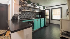 A kitchen with teal cabinets, a black countertop, a microwave, and a refrigerator.