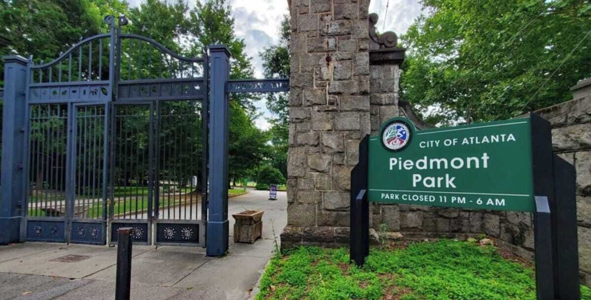 A gated entrance to Piedmont Park with a sign indicating it is closed from 11 PM to 6 AM.