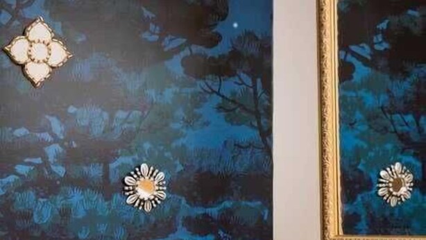 A room with a desk, a mirror, and a wall mural of trees.