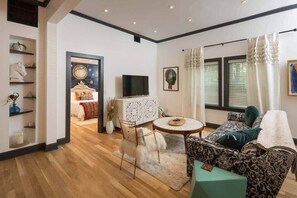 A living room with a sofa, a round coffee table, a TV, and a decorative cabinet.