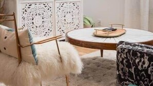 A modern living room with a flat-screen TV, a round coffee table, and a white cabinet with intricate carvings.