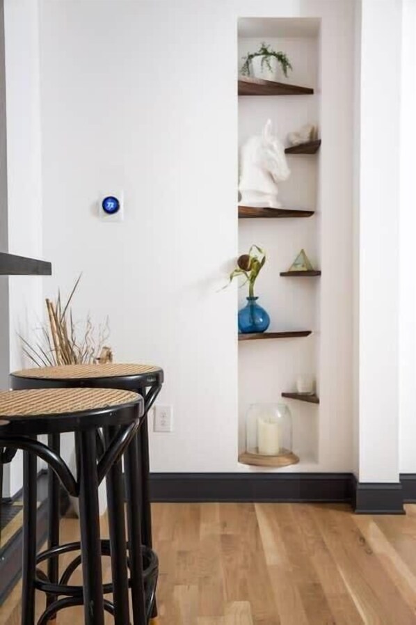 A room with a white wall, a built-in shelf with decorative items, and a wooden floor.
