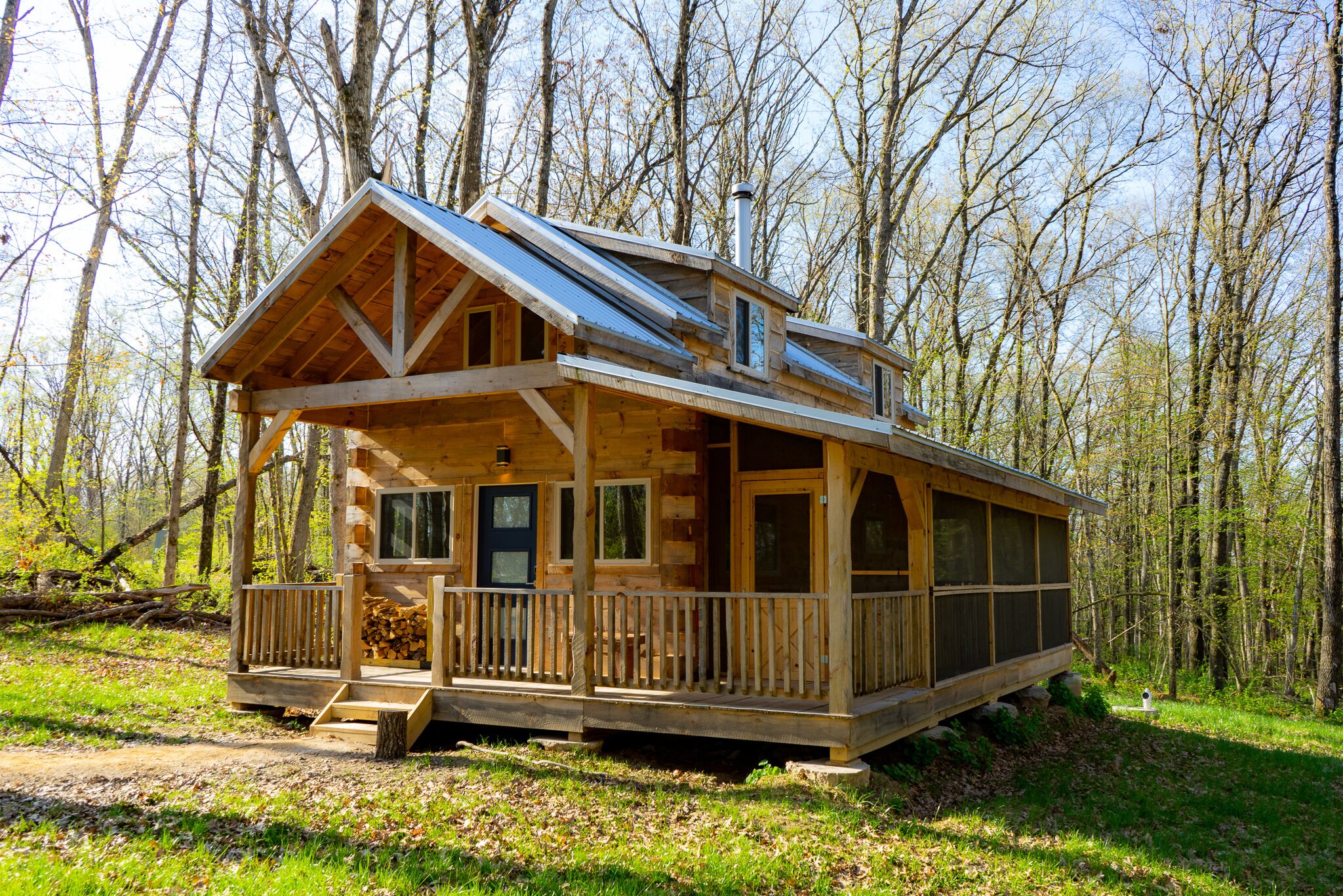 A wooden cabin with a porch, large windows, and a chimney.