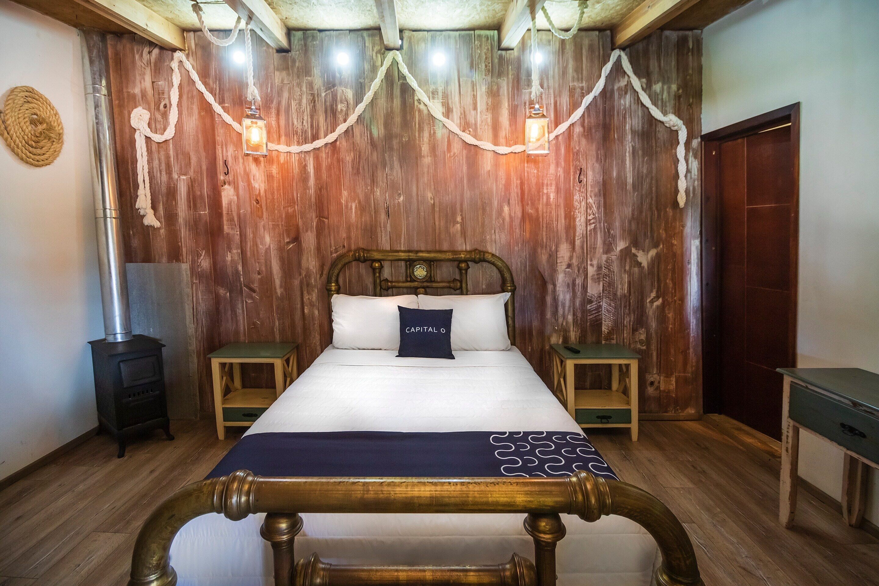 A wooden-paneled bedroom with a bed, two bedside tables, a nightstand, and a wooden bench.