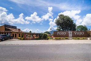 A building with a sign reading "Pozo Viejo" and a parked car in front. - Pozo Viejo (Zacapoaxtla)