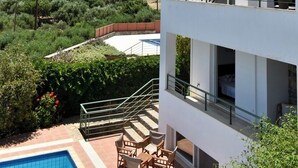 A modern two-story building with a balcony, a pool, and a view of a mountainous landscape.
