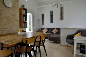 Un salon moderne avec une table à manger en bois, des chaises, un canapé et une bibliothèque.
