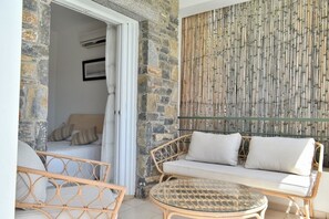 A room with a stone wall, a woven sofa, a wicker chair, and a glass table.