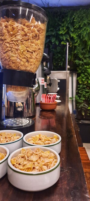 A cereal dispenser with bowls of cereal in front. - Huella Andina (San Carlos de Bariloche)
