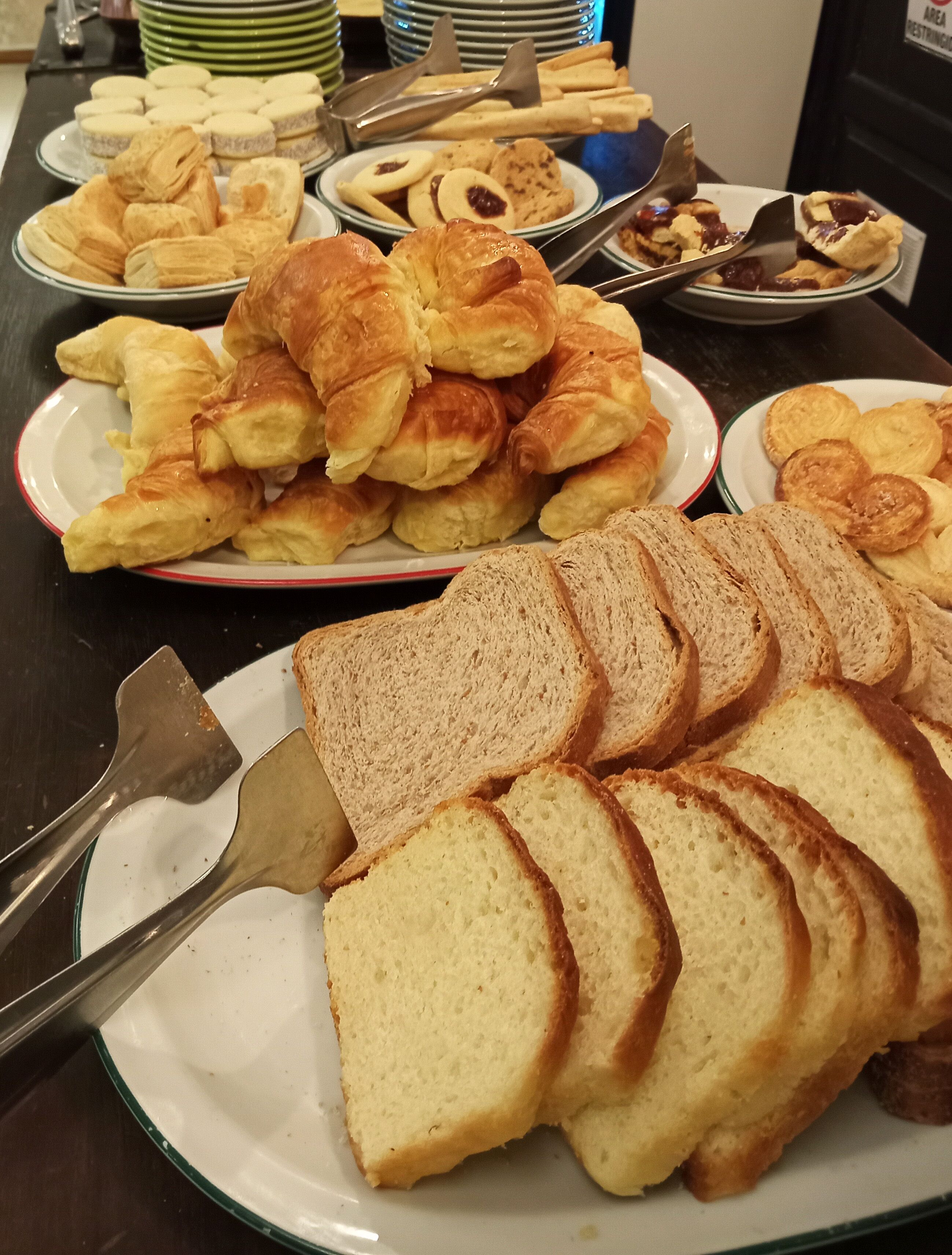 A buffet with various food items including bread, pastries, and cookies.