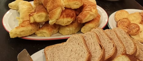A buffet with various food items including bread, pastries, and cookies.