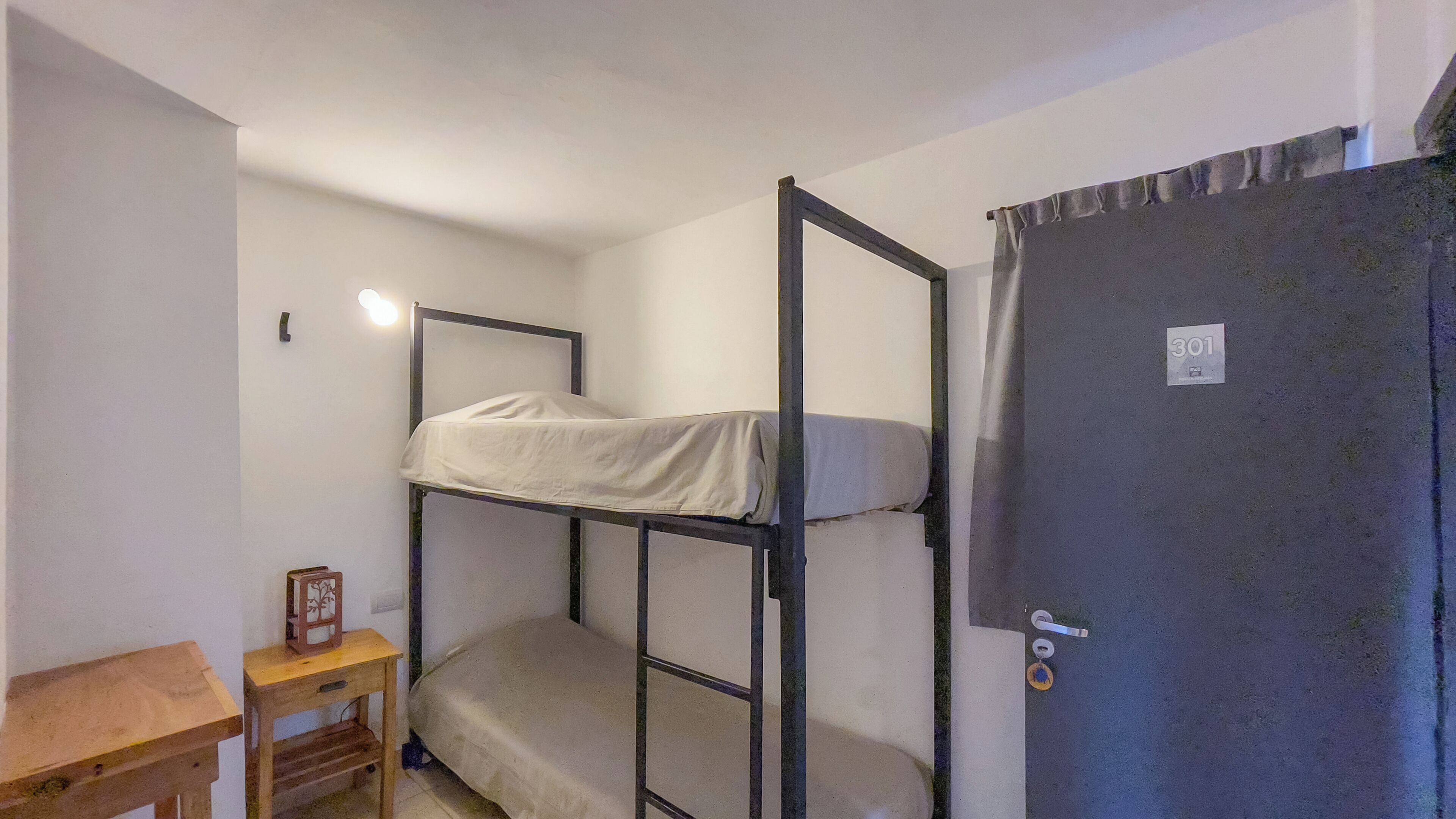 Een slaapkamer met stapelbed, een klein houten tafeltje en een deur met een nummerbord.