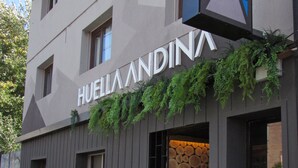 Ein Gebäude mit der Aufschrift "HUEILLA ANDINA" und einer Wand aus Holzstämmen.