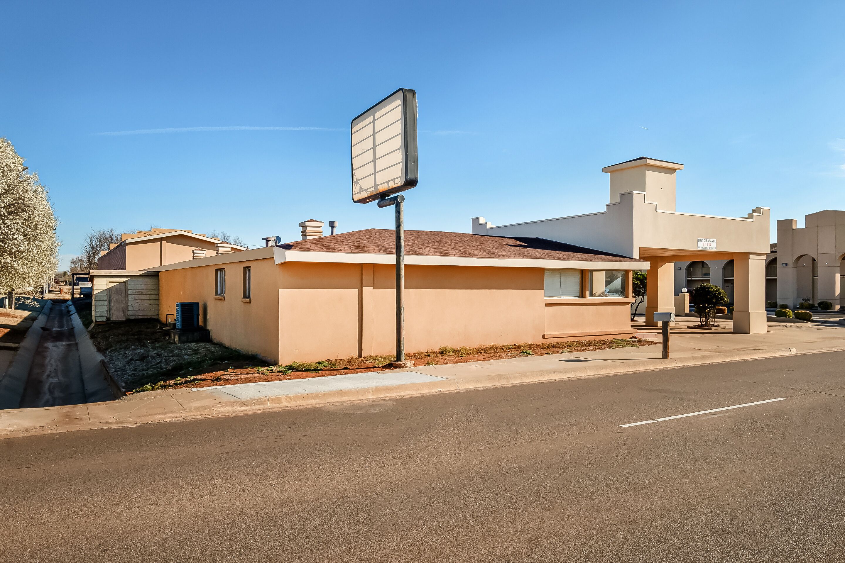 A single-story building with a beige facade, a flat roof, and a large blank signboard.